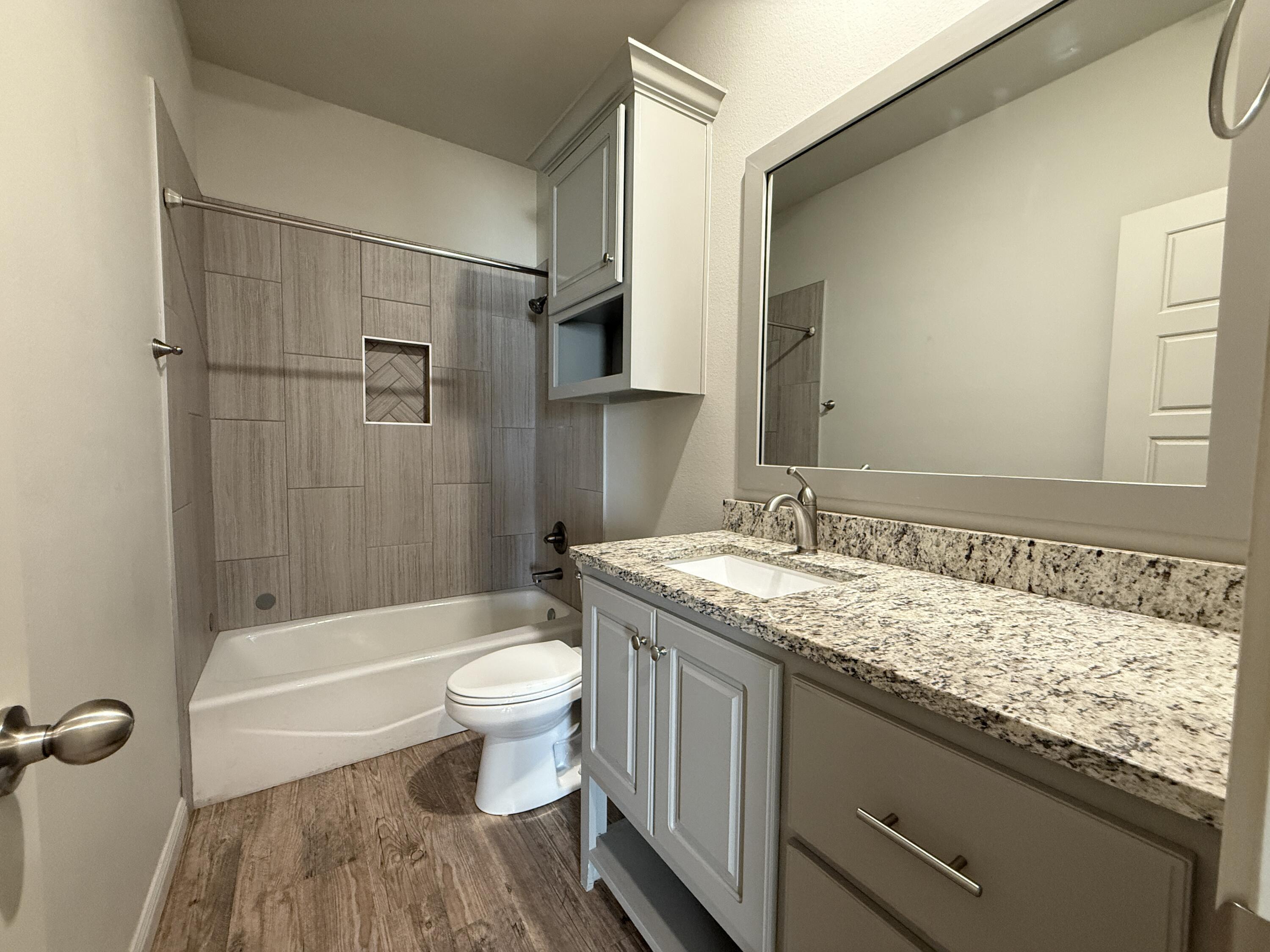 7504 87th Street Lubbock, TX 79424 - Photo 23 of 33 a bathroom with a granite countertop sink toilet and shower