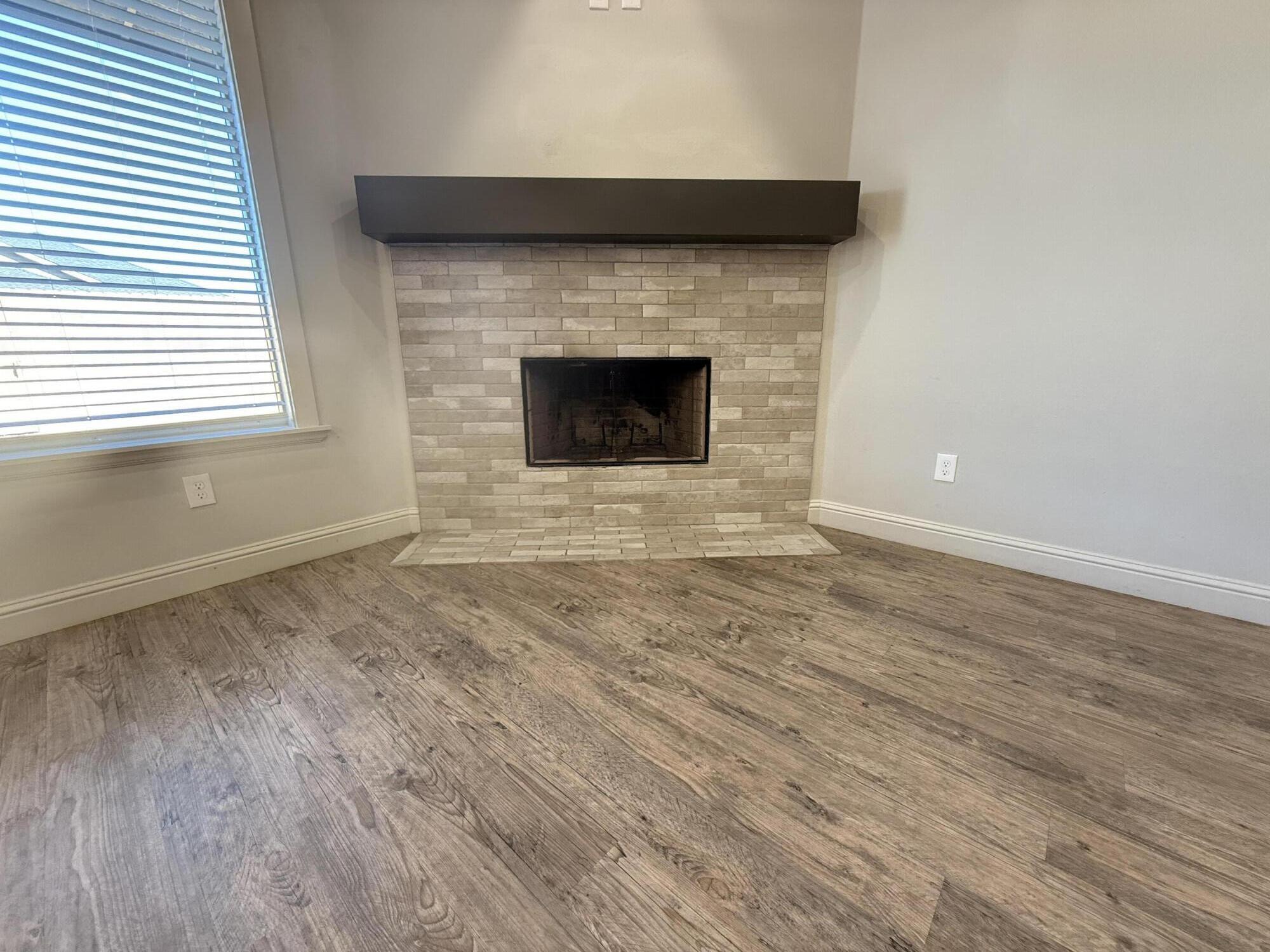 7504 87th Street Lubbock, TX 79424 - Photo 5 of 33 a view of empty room with wooden floor and a fireplace