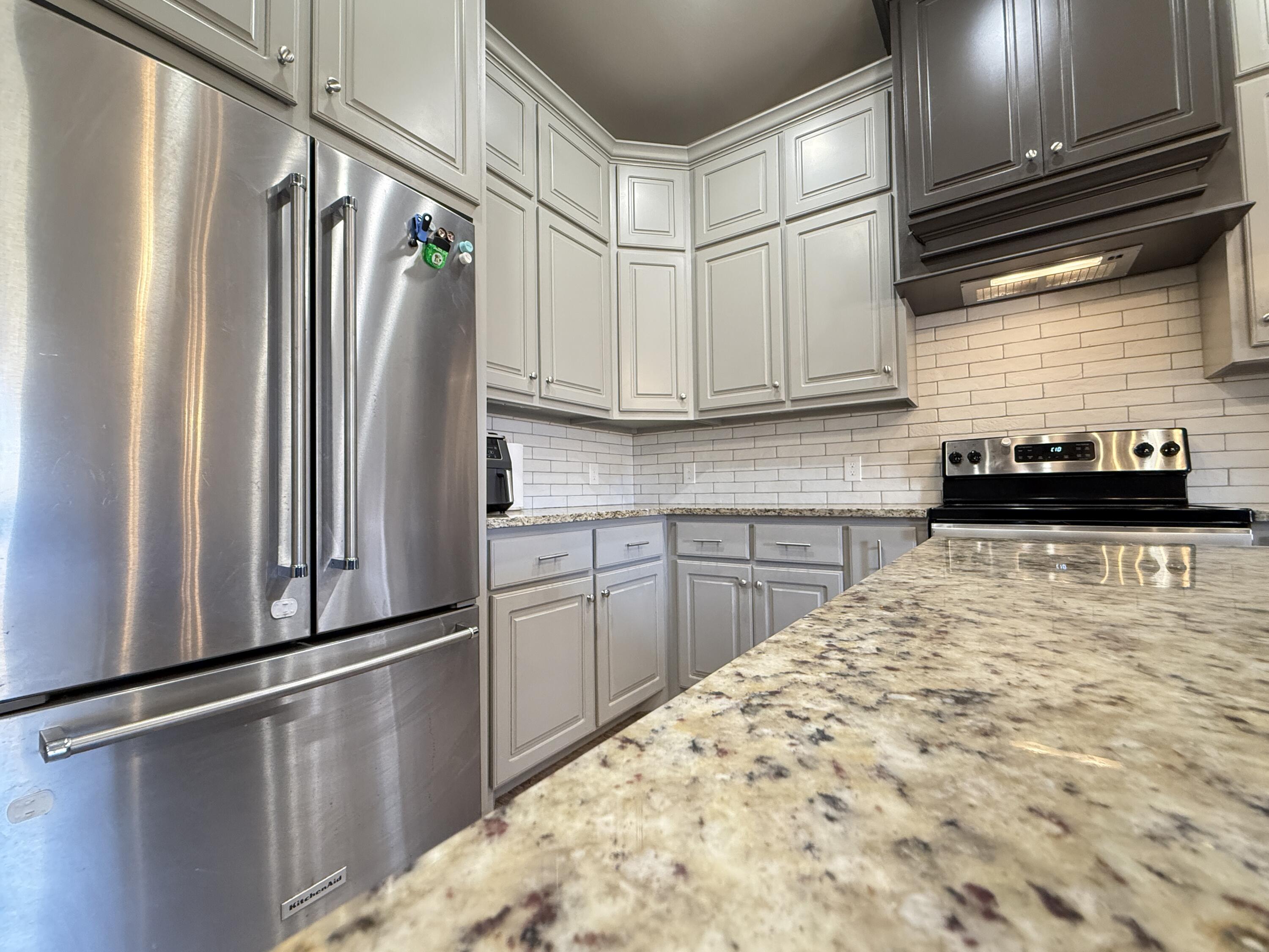 7504 87th Street Lubbock, TX 79424 - Photo 7 of 33 a kitchen with granite countertop a refrigerator and a sink