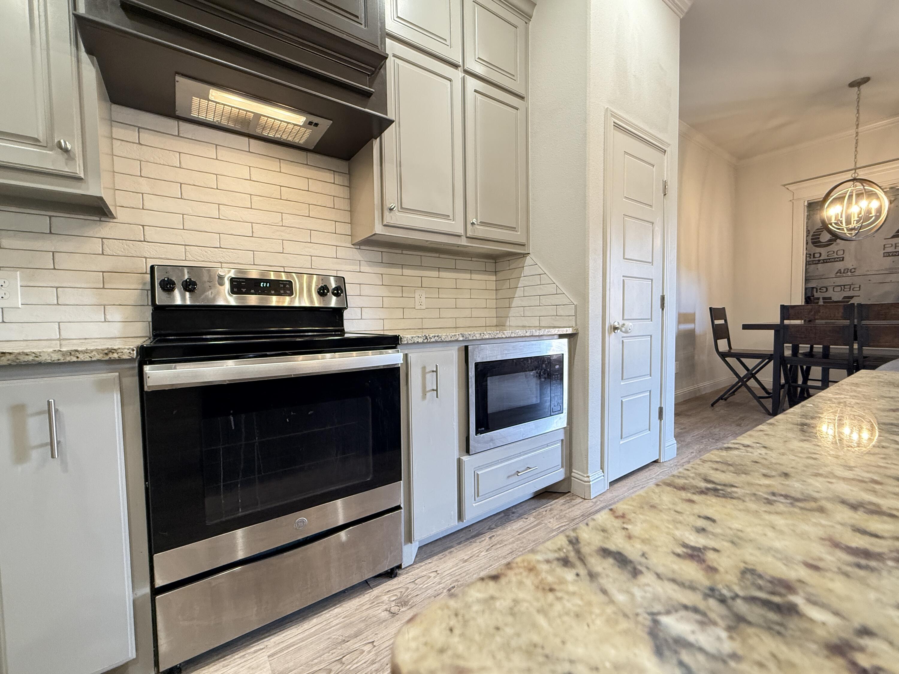 7504 87th Street Lubbock, TX 79424 - Photo 8 of 33 a kitchen with granite countertop cabinets stainless steel appliances and wooden floor