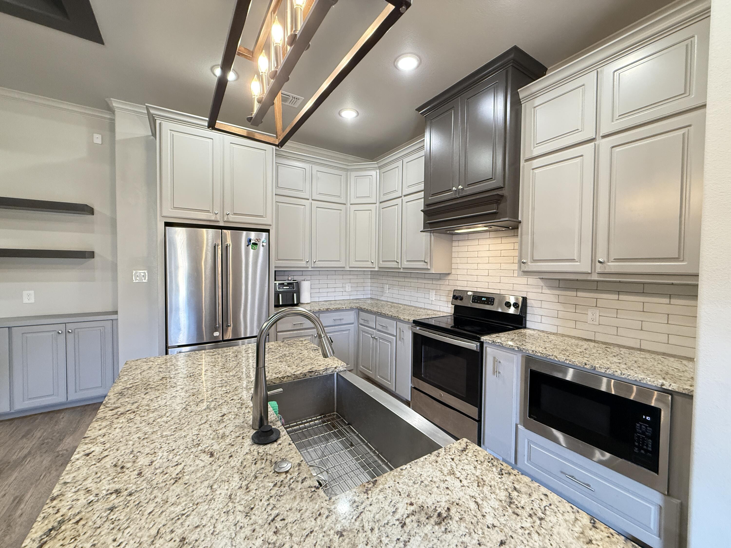 7504 87th Street Lubbock, TX 79424 - Photo 9 of 33 a kitchen with granite countertop stainless steel appliances a stove refrigerator and cabinets