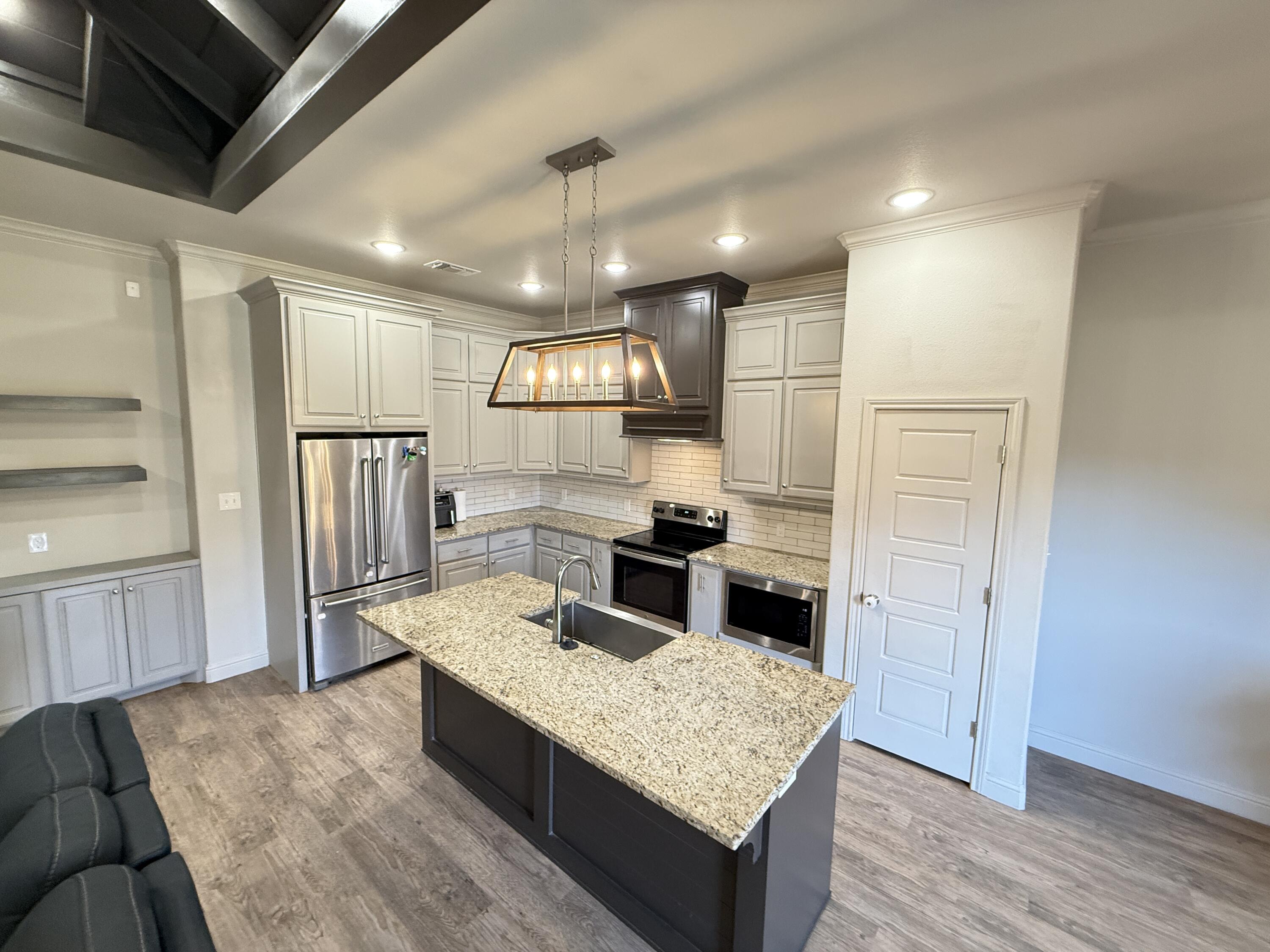 7504 87th Street Lubbock, TX 79424 - Photo 10 of 33 a kitchen with a refrigerator a sink and wooden floor