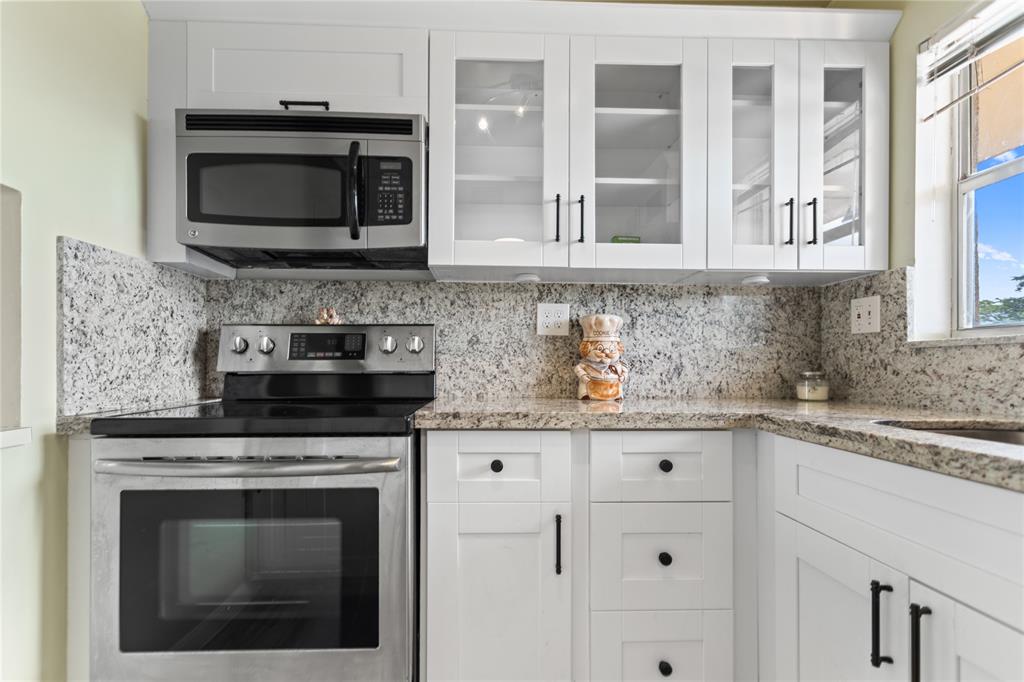 2720 North Pine Island Road, Unit 307 Sunrise, FL 33322 - Photo 15 of 40 a kitchen with granite countertop white cabinets stainless steel appliances and a sink