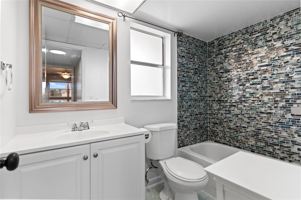 2720 North Pine Island Road, Unit 307 Sunrise, FL 33322 - Photo 30 of 40 a bathroom with a granite countertop toilet a sink a mirror and a shower