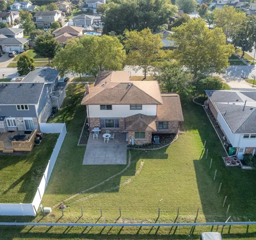 an aerial view of a house with swimming pool and large trees