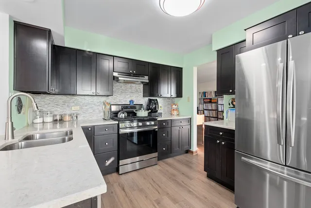 a kitchen with stainless steel appliances granite countertop a refrigerator stove and sink