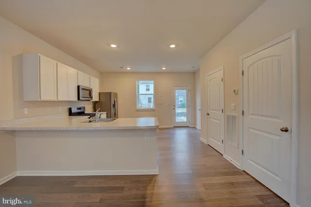 a view of a kitchen with kitchen island granite countertop a refrigerator oven a sink dishwasher with wooden cabinets and floor