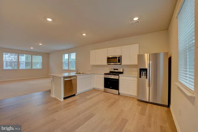 a kitchen with granite countertop a refrigerator and wooden floor