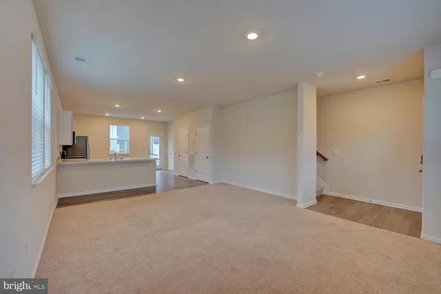 a view of an empty room and a kitchen