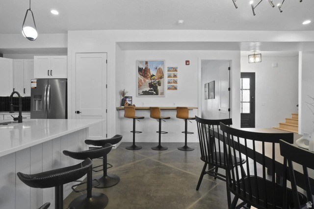 4346 Canterbury Road Hurricane, UT 84737 - Photo 7 of 37 Kitchen with concrete flooring, white cabinets, a kitchen bar, stainless steel fridge, and hanging light fixtures