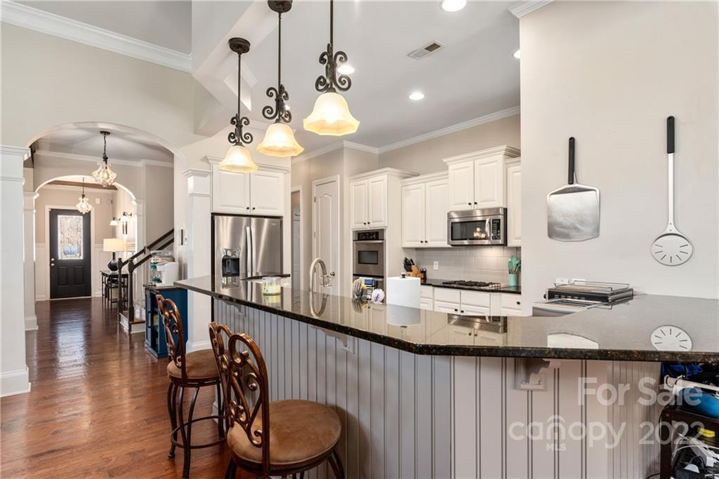 1235 Gold Rush Court Fort Mill, SC 29708 - Photo 20 of 42 a kitchen with stainless steel appliances granite countertop a stove a sink a dining table and chairs with wooden floor