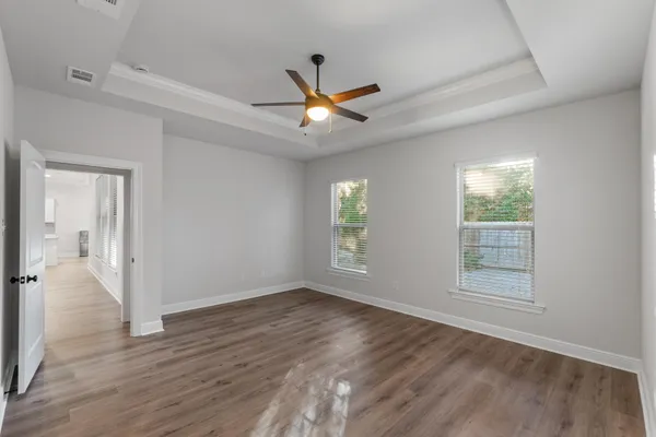 a view of an empty room and wooden floor and a ceiling fan