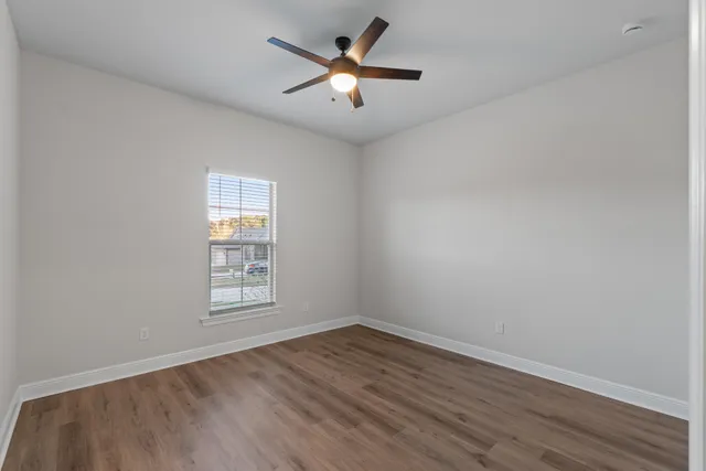 an empty room with wooden floor and ceiling fan