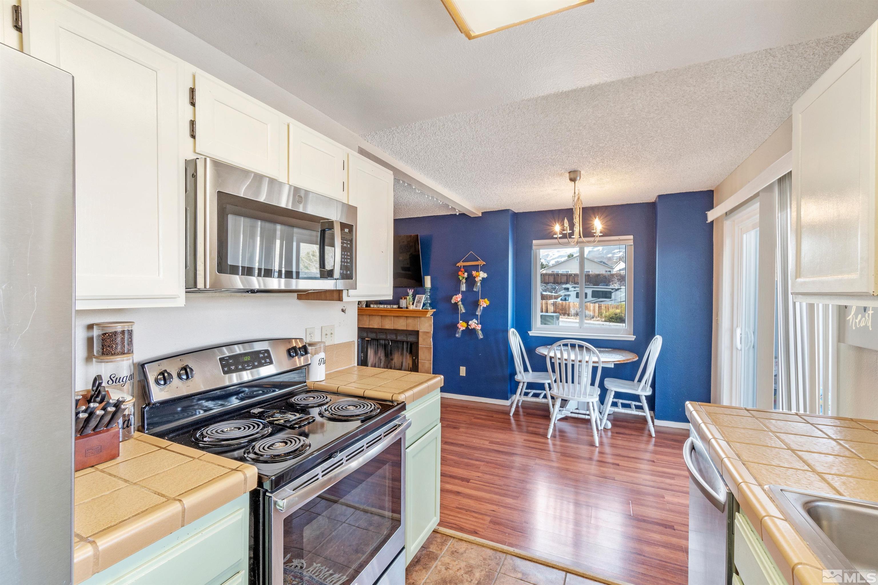 3971 Kings Row Reno, NV 89503 - Photo 16 of 29 a kitchen with stainless steel appliances granite countertop a stove top oven a dining table and chairs with wooden floor