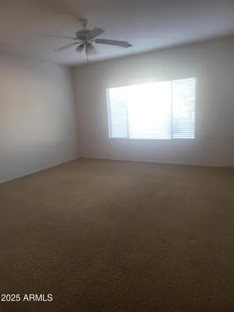 an empty room with a window and a ceiling fan