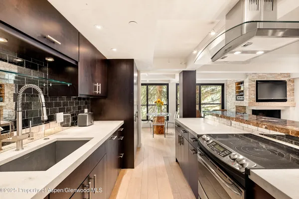 a large kitchen with a large counter top a sink stainless steel appliances and cabinets