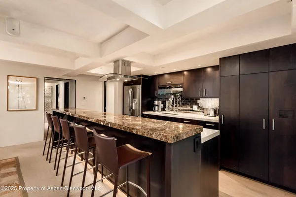 a kitchen with stainless steel appliances granite countertop a table chairs sink and cabinets