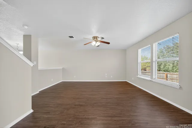 a view of empty room with wooden floor and fan