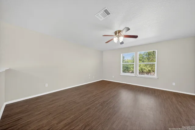 an empty room with wooden floor and ceiling fan