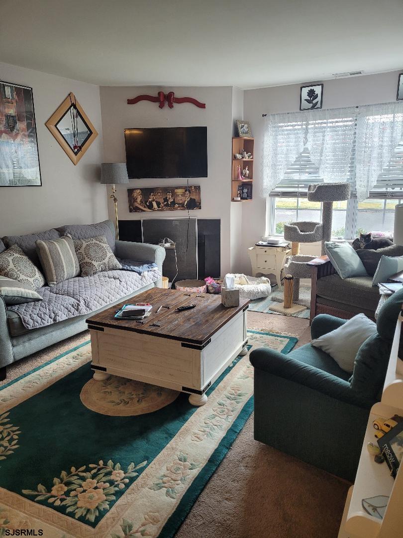 14 Meadow Ridge Road, Unit 14 Smithville, NJ 08205 - Photo 3 of 8 a living room with furniture a flat screen tv and a fireplace