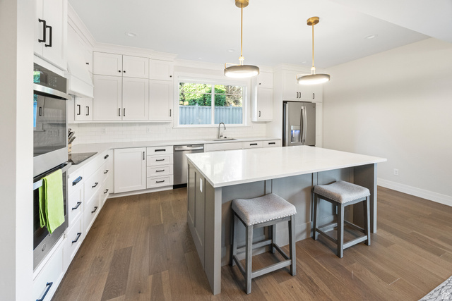 1774 Country Club Drive Logan, UT 84321 - Photo 6 of 28 Modern kitchen featuring white cabinetry with black hardware, stainless steel appliances, and wood-finish flooring