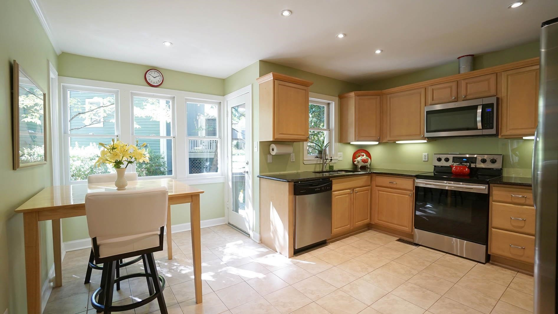 1809 Falls Church Road Raleigh, NC 27609 - Photo 6 of 56 a kitchen with stainless steel appliances granite countertop a stove a sink a microwave a dining table and chairs