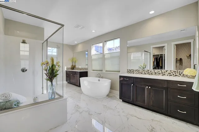 a bathroom with a double vanity sink mirror and tub