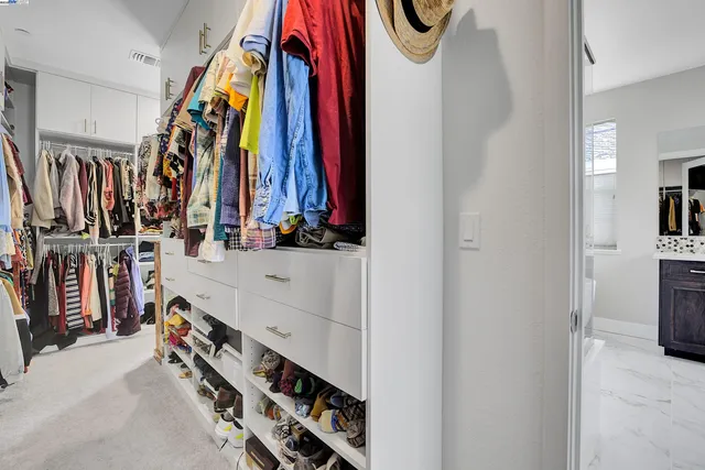 a view of walk in closet with clothes and shoes