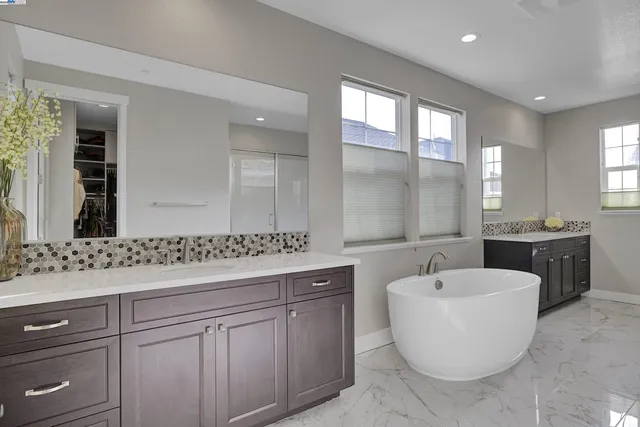 a bathroom with a white tub a vanity a sink and a large mirror