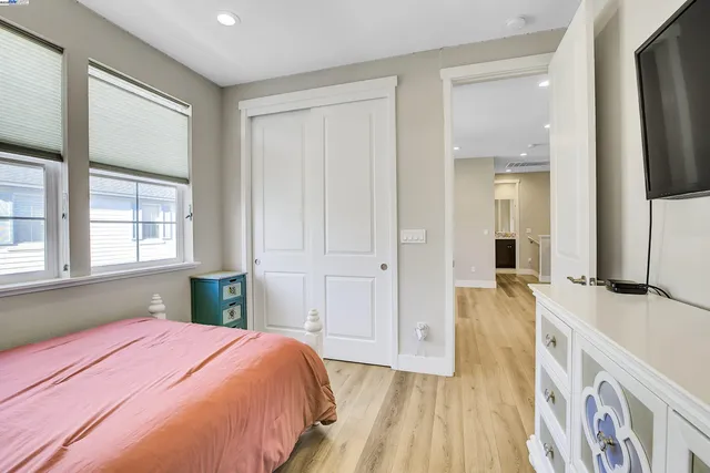 a bedroom with a bed and a large mirror next to a window