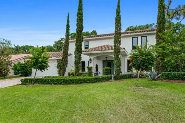 a view of a white house with a big yard and potted plants