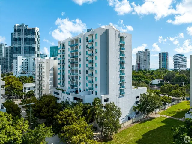a view of a multi story residential apartment building with a yard and plants