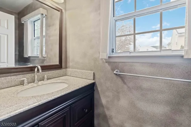 a bathroom with a granite countertop sink and a window