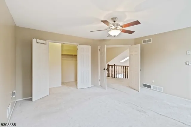 a view of an empty room with chandelier fan and a window