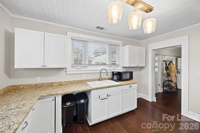 a kitchen with a sink dishwasher a stove and white cabinets with wooden floor