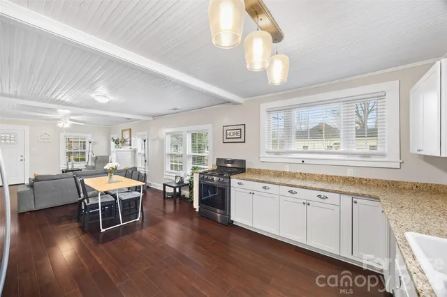 a living room with stainless steel appliances granite countertop furniture wooden floor and a window