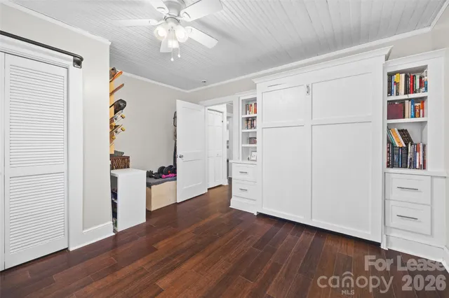 an empty room with wooden floor closet and windows