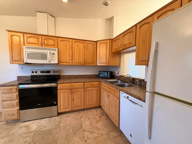 a kitchen with stainless steel appliances granite countertop a stove a sink and a microwave