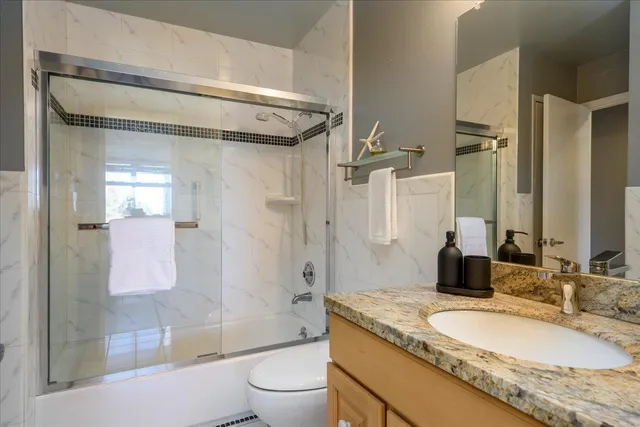 a bathroom with a granite countertop sink toilet mirror and shower