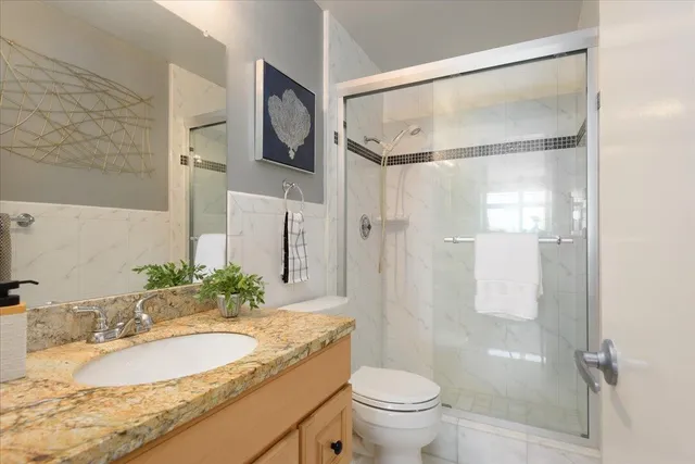 a bathroom with a granite countertop sink toilet and shower