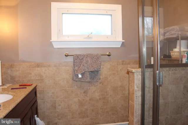 a bathroom with a granite countertop sink a mirror and a shower