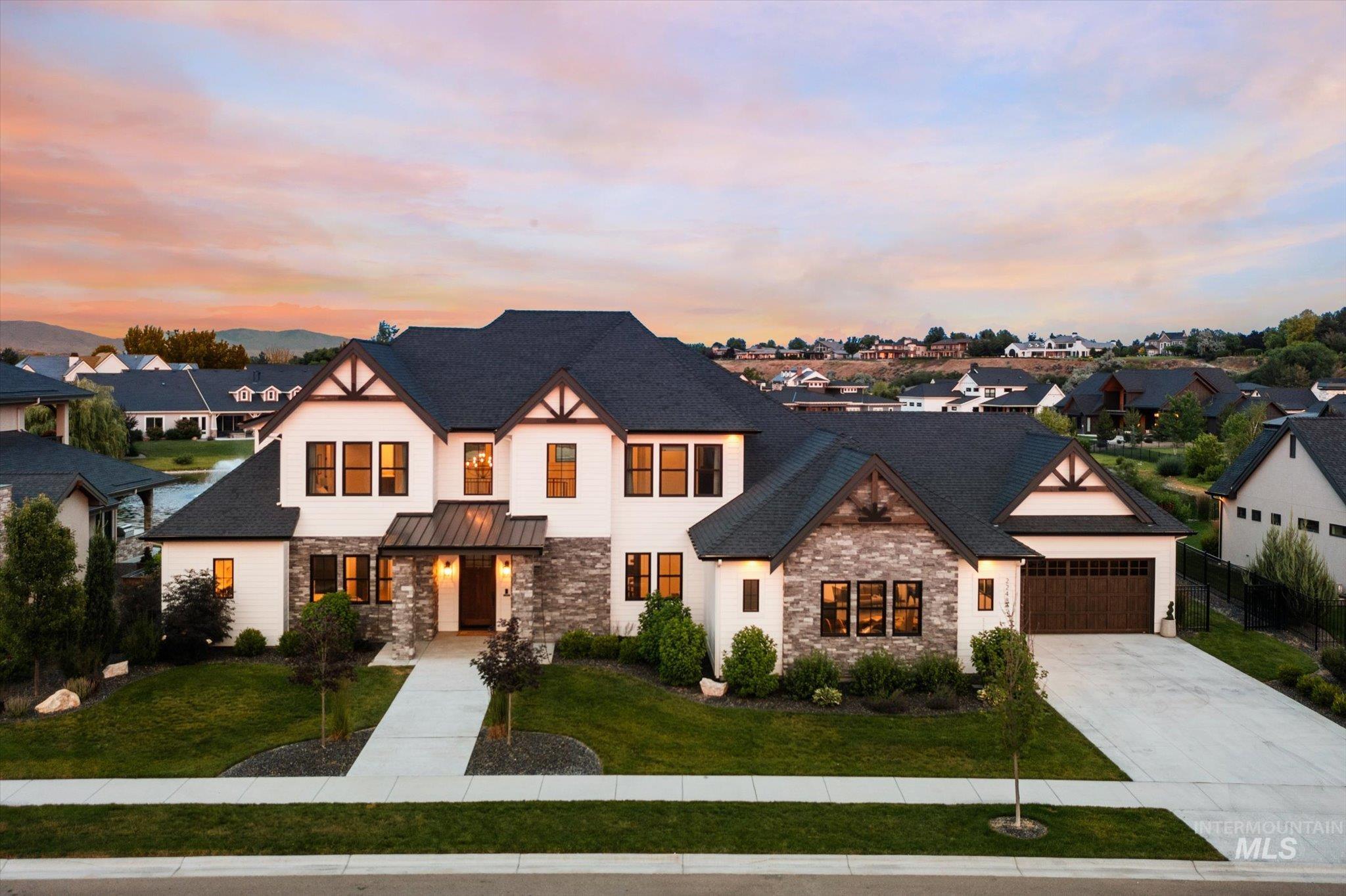 View of front of house with stone siding, concrete driveway, a standing seam roof, a residential view, and an attached garage