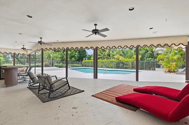 a living room with furniture floor to ceiling window and a ceiling fan
