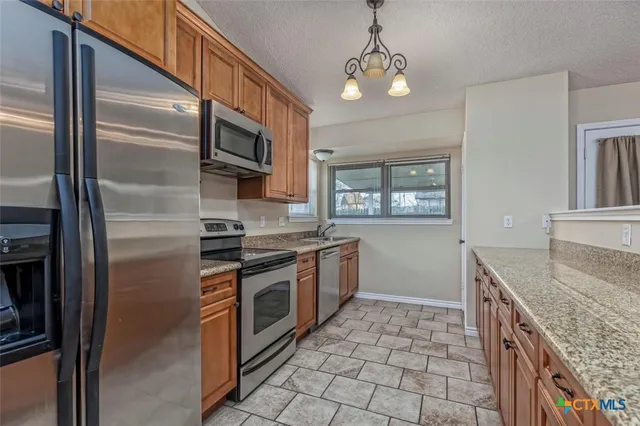 a kitchen with stainless steel appliances granite countertop a refrigerator a stove and a sink