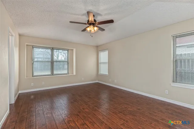 a view of empty room with wooden floor and fan
