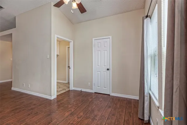 an empty room with wooden floor cabinet and windows