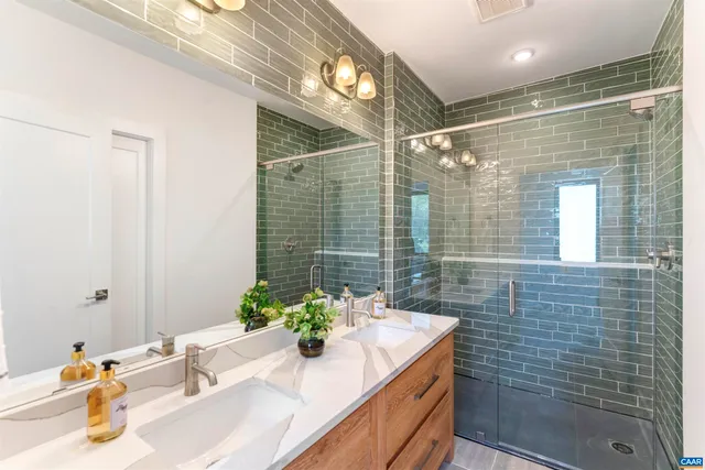 a bathroom with a granite countertop sink a mirror and shower