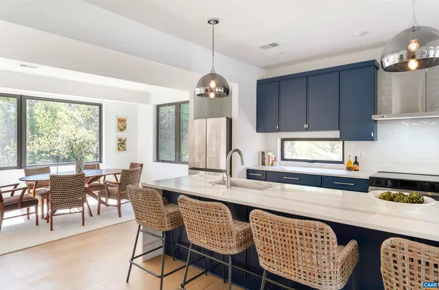 a kitchen with a dining table chairs and large windows