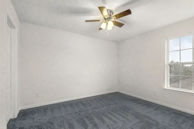 an empty room with a window and a ceiling fan