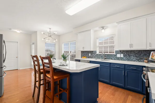 a kitchen with stainless steel appliances kitchen island granite countertop a table chairs sink and cabinets